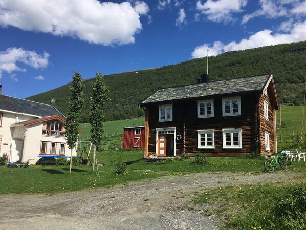 A wooden house with a sloped roof, a front porch, and a visible chimney. - Old log cabin from 1830 with soul. (Trøndelag)