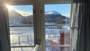 A room with a view of a snowy landscape through a window. - Old log cabin from 1830 with soul. (Trøndelag)