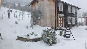 A two-story wooden house with a snow-covered roof and a swing set in the yard. - Old log cabin from 1830 with soul. (Trøndelag)