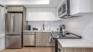 A modern kitchen with stainless steel appliances, wooden cabinets, and a white tiled backsplash. - Capitol Hill Suites - Unit 3 (Washington)