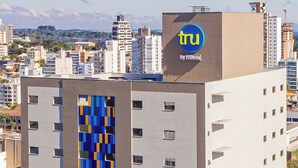 A modern hotel building with a distinctive blue and yellow patterned facade, multiple floors, and a visible "tru by Hilton" sign on the top.