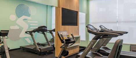 A gym with treadmills, a stationary bike, and a wall-mounted TV.