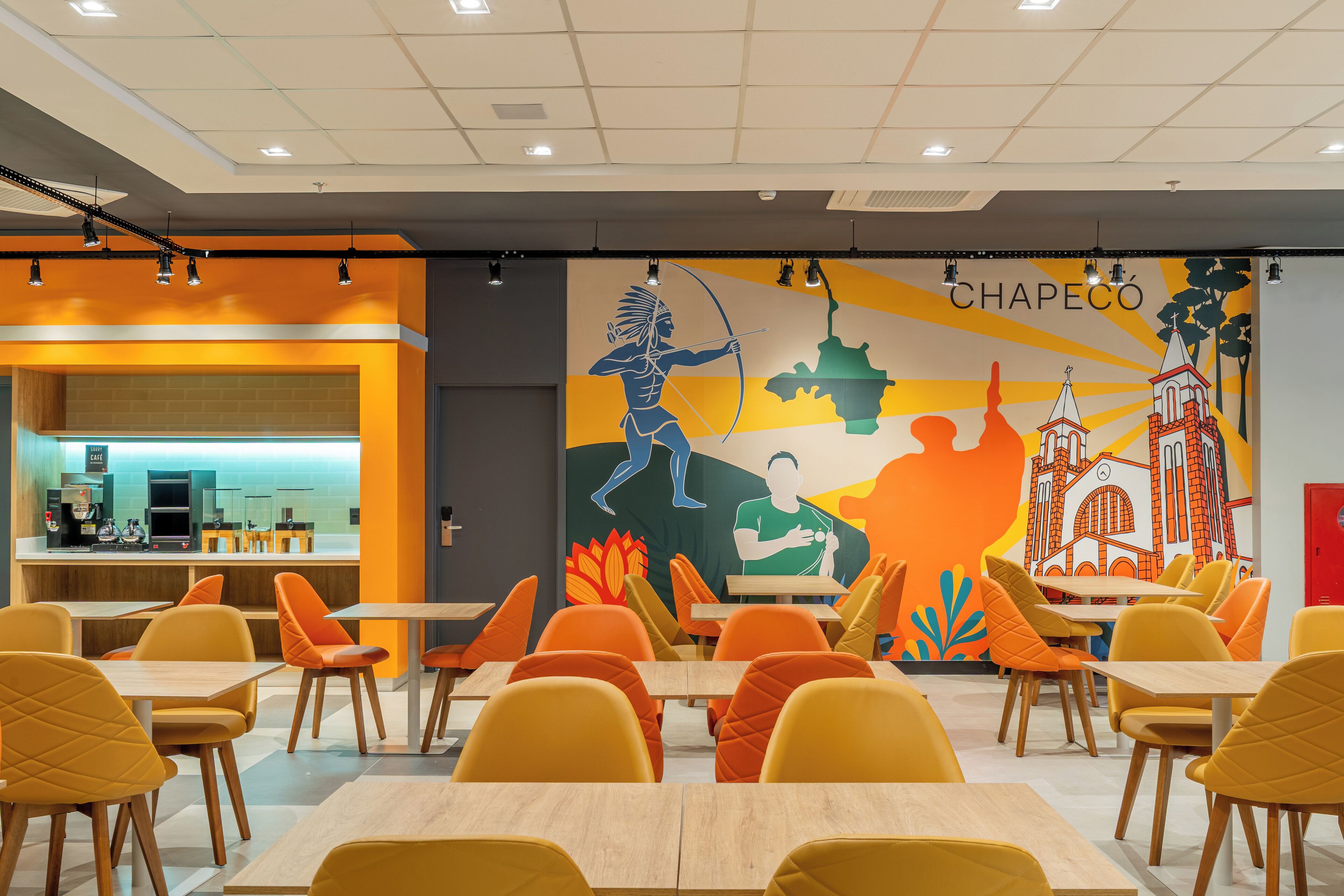 A dining area with tables and chairs, a mural with cultural artwork, and a counter with a coffee machine.