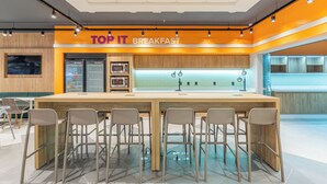 A breakfast area with a long counter and bar stools, equipped with a microwave and refrigerator.
