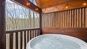 Un jacuzzi en una terraza de madera con vistas a árboles.