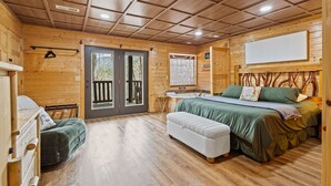 Una cabaña de madera con una cama, un banco y una mesita.
