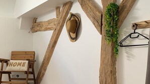 A room with wooden beams, a bench with a 'DREAM' pillow, a hat on the wall, and a 'HOME' pillow on a chair.
