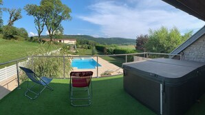 A balcony with artificial grass, a pool, and a view of the countryside.