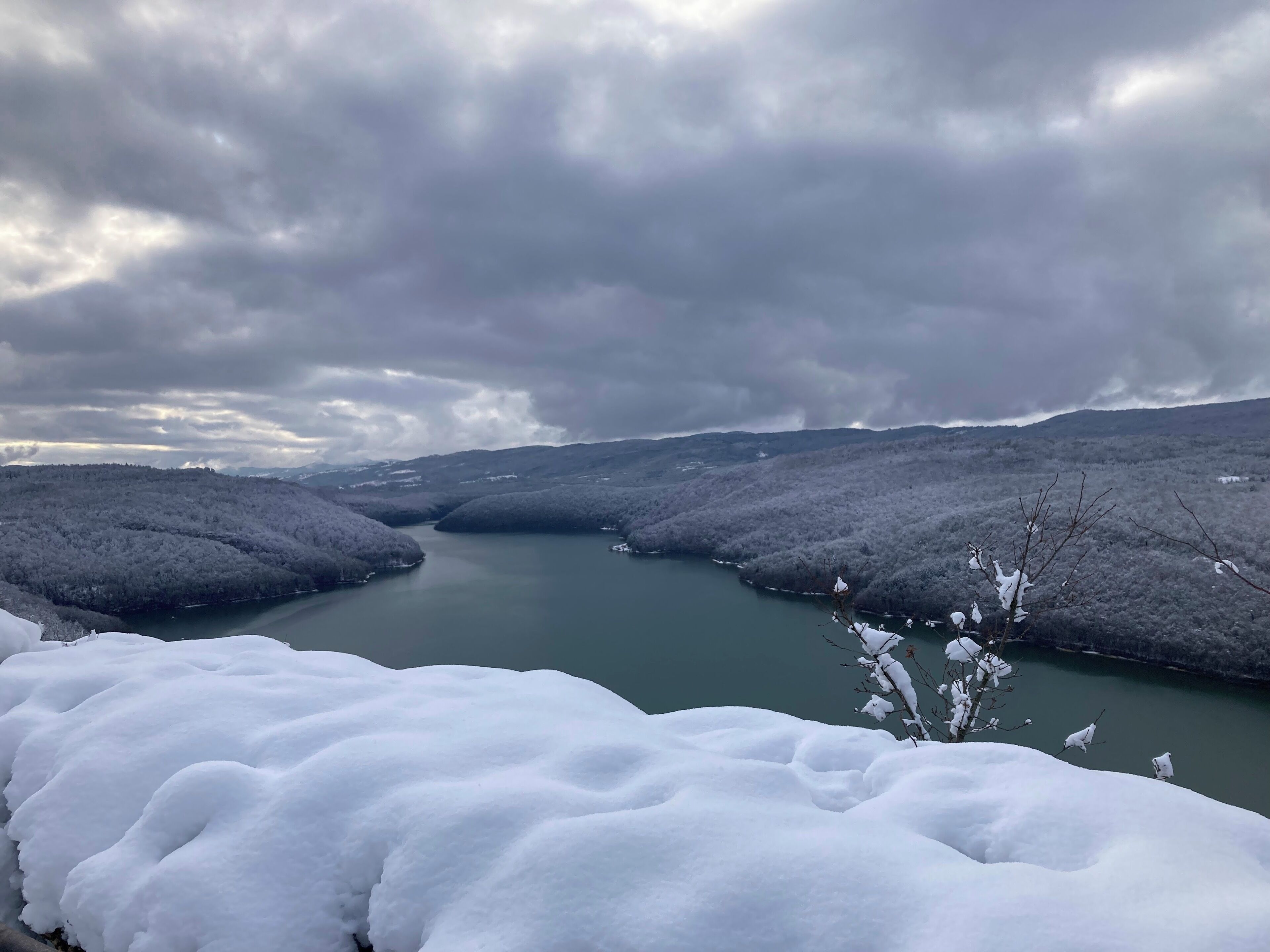 A snow-covered landscape with a river and hills.