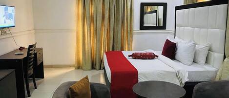 Una habitación de hotel con una cama, un escritorio, una silla, un sofá y una mesita.