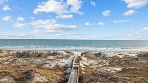 A beach with a wooden boardwalk leading to the shore. - Sunset Beach 3BR Cottage with Spacious Deck & Screened Porches (Sunset Beach)
