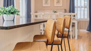 Een moderne keuken met een marmeren aanrecht, twee bruine leren stoelen en een potplant.