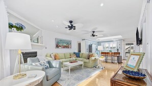Een ruime woonkamer met een bank, salontafel en een eethoek met stoelen.