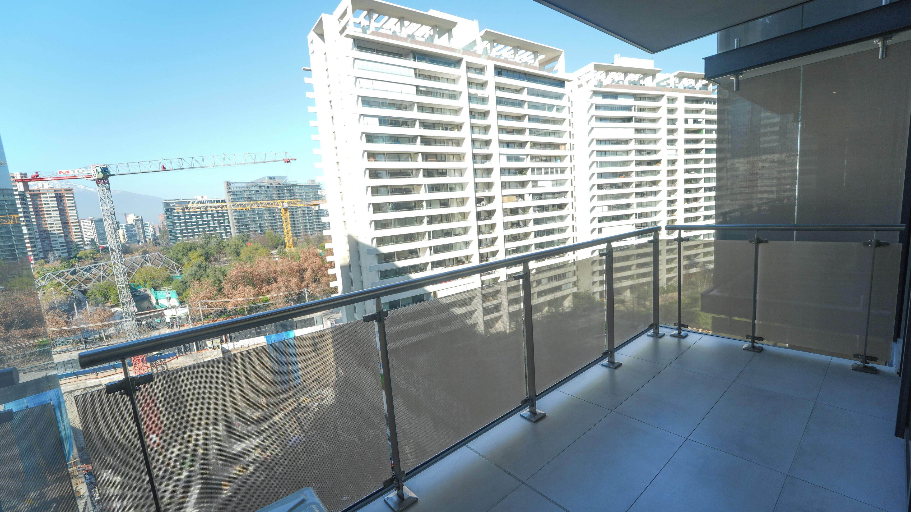 A high-rise building with multiple balconies and a construction crane in the background.
