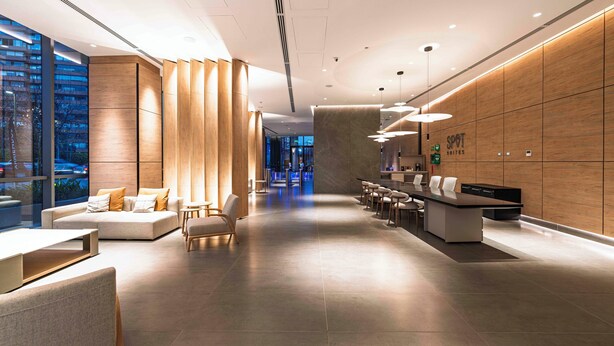 A modern hotel lobby with a reception desk, seating area, and large windows offering city views. - Spot Suites (Santiago)