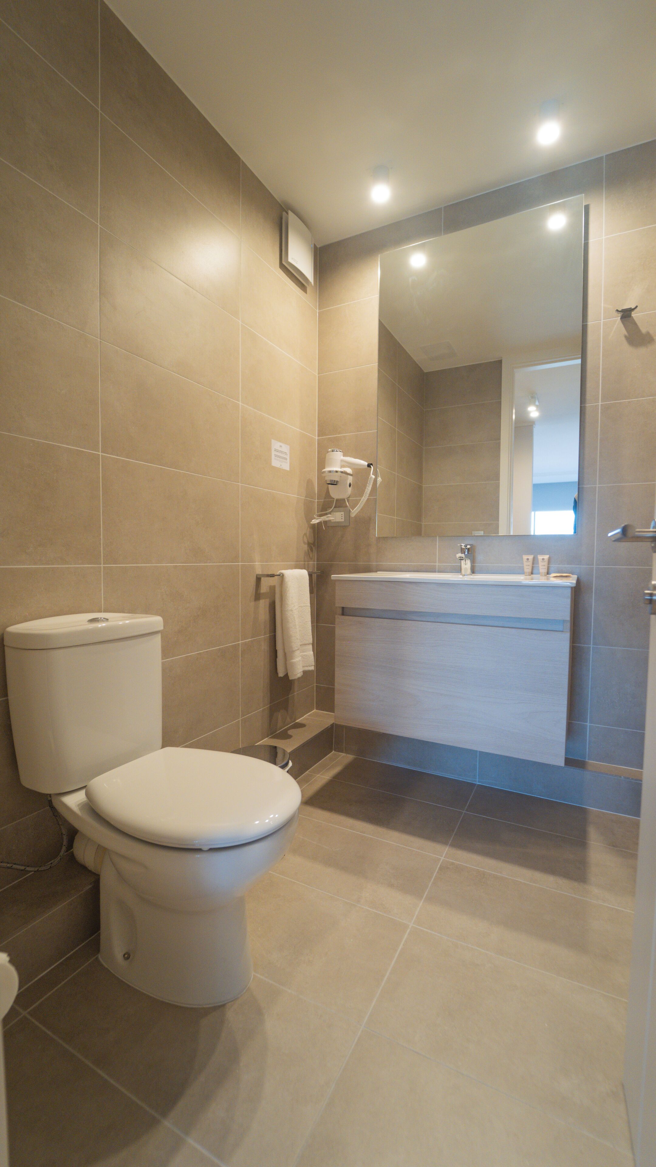 Un baño moderno con inodoro, lavamanos y zona de ducha.