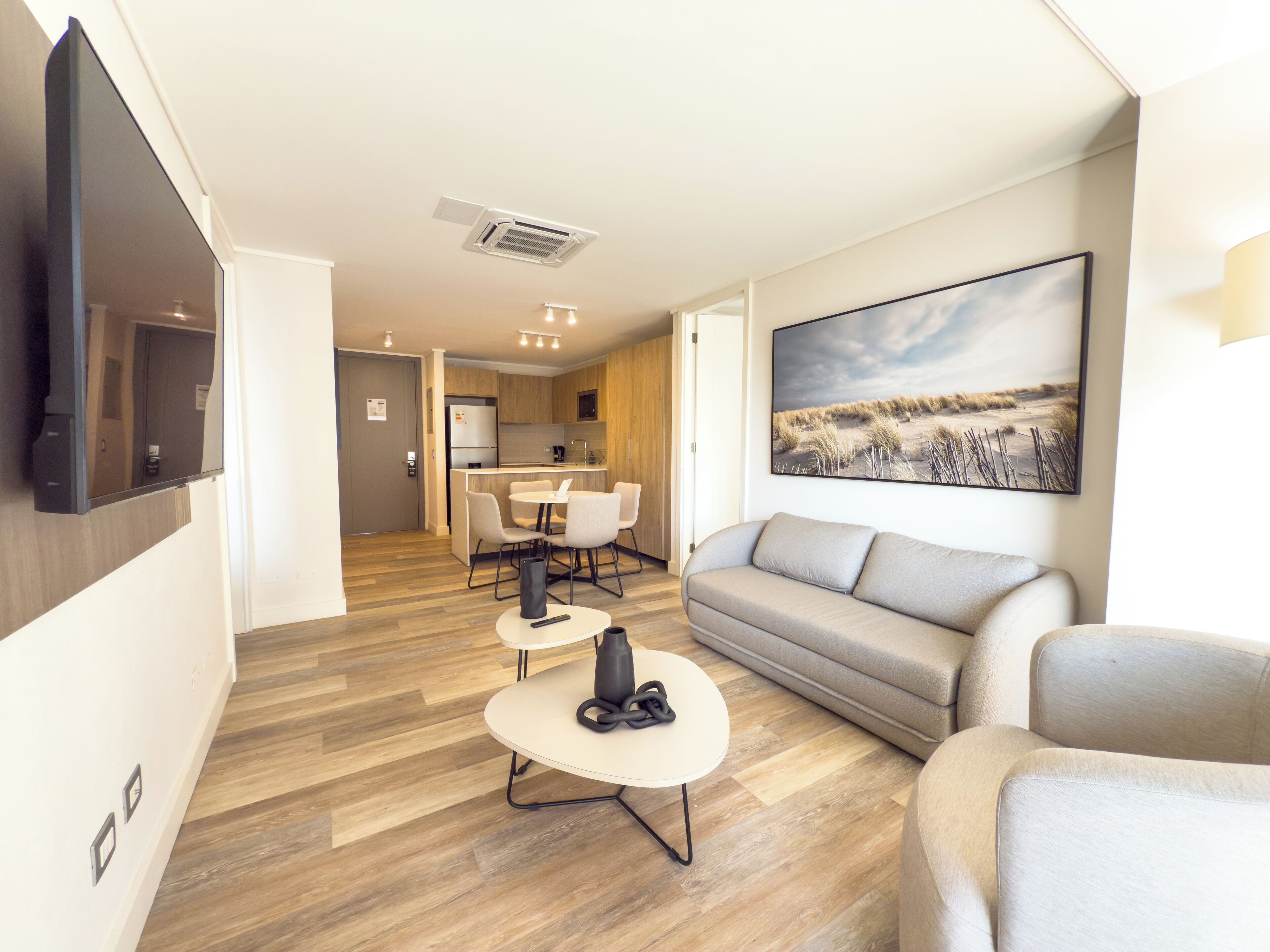 A modern living room with a sofa, a coffee table, and a dining area with chairs and a table.