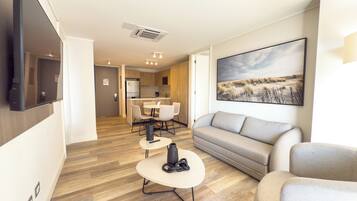 A modern living room with a sofa, a coffee table, and a dining area with chairs and a table.