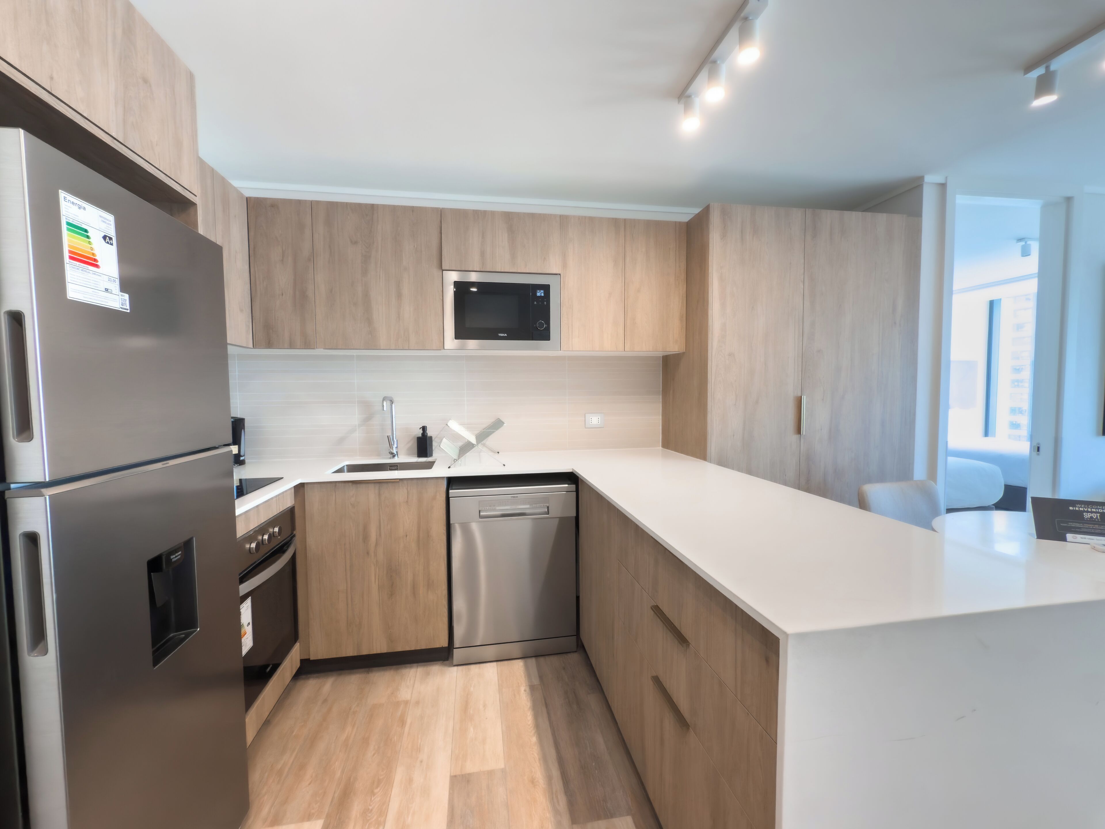 A modern kitchen with wooden cabinets, stainless steel appliances, and a white countertop.