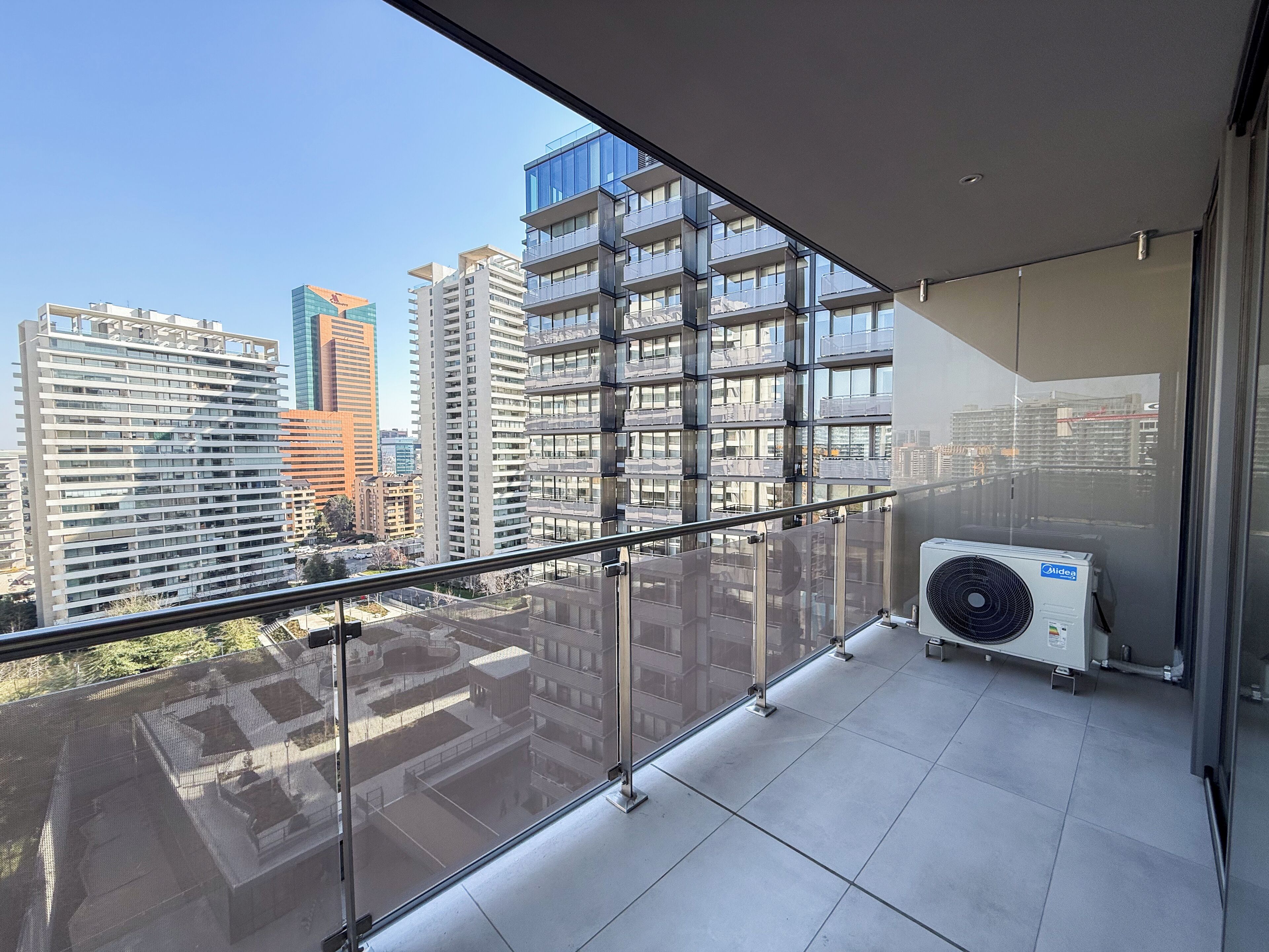 A balcony with a glass railing overlooking a cityscape with modern buildings.