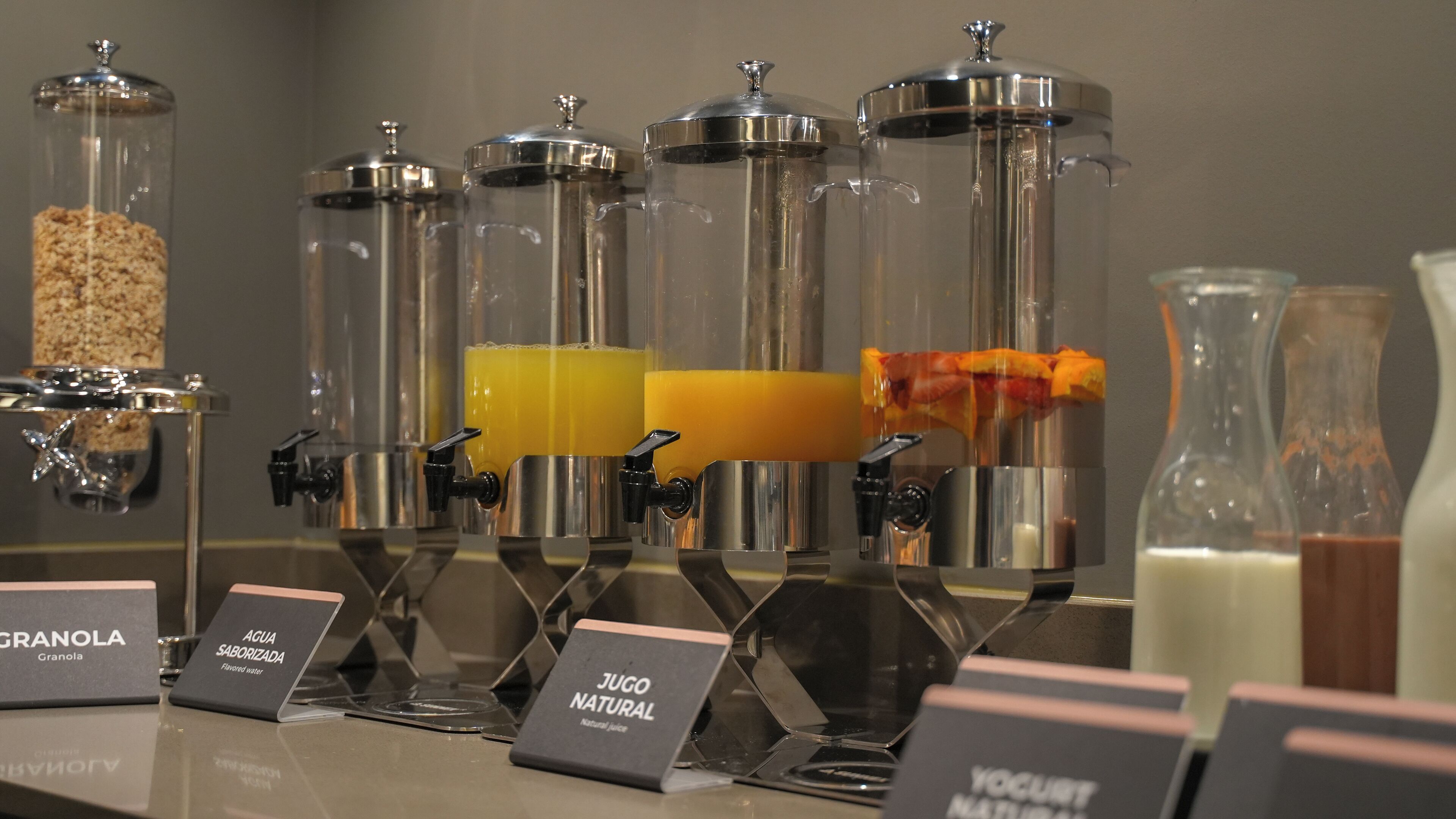 Un bar de zumos con varios recipientes de jugos naturales y granola.