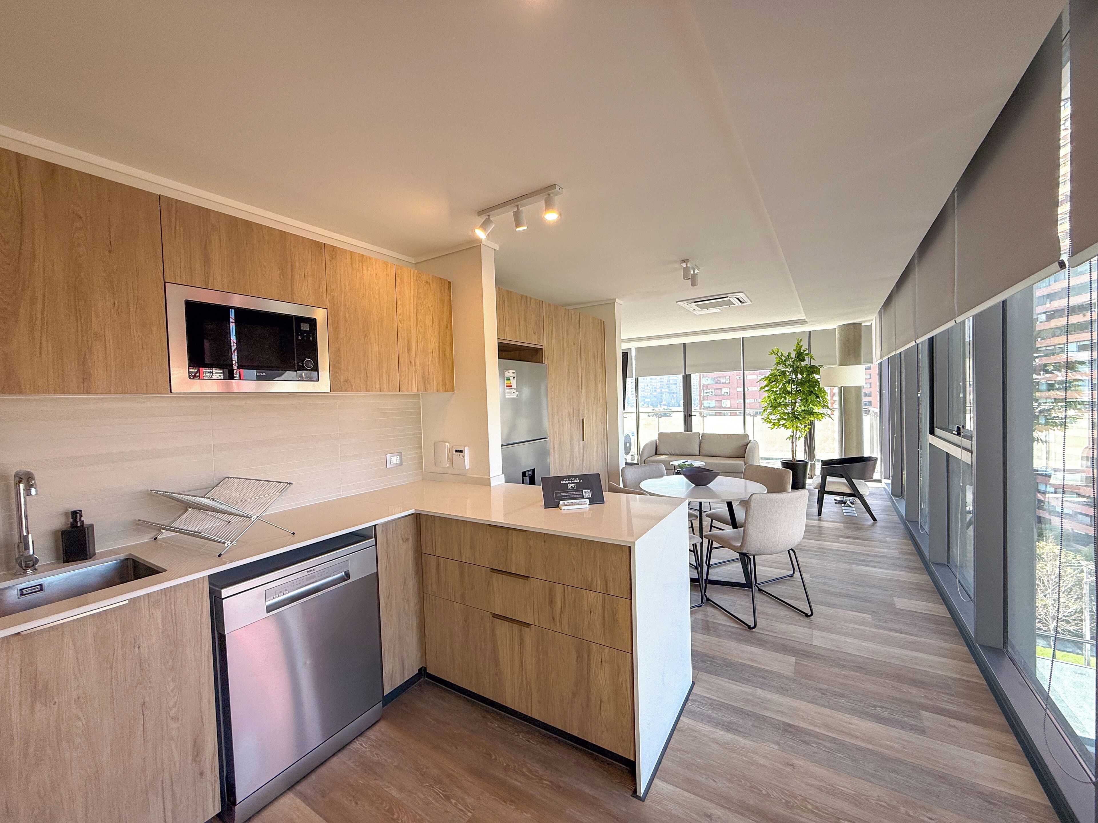 Una cocina moderna con armarios de madera, electrodomésticos de acero inoxidable y un comedor con mesa y sillas.