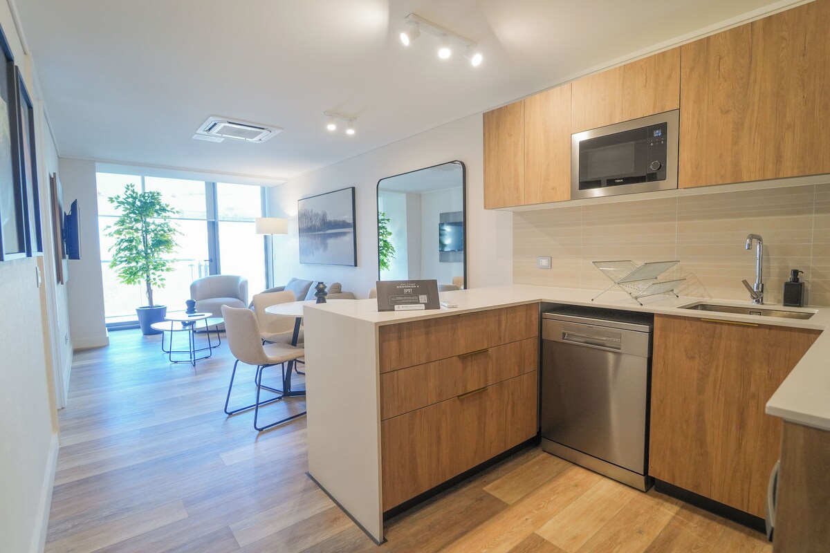 A modern kitchen with wooden cabinets, a built-in microwave, and a dishwasher.