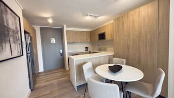 A modern kitchen with a dining area, featuring a built-in microwave, stainless steel appliances, and a white countertop.