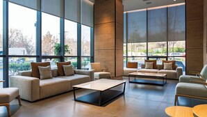 A spacious lobby with large windows, a sofa set, and a coffee table. - Spot Suites (Santiago)