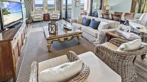 Un salon spacieux doté d’un grand téléviseur, de sièges confortables et offrant une vue sur l’océan.