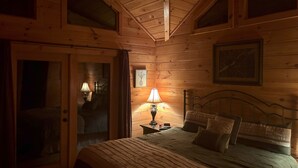 A cozy wooden room with a bed, two bedside lamps, a ceiling fan, and a framed picture on the wall. - BLUE RIDGE SPLENDOR - 3 BR, 3 BA amazing cabin, with incredible mountain views! (Cherry Log)
