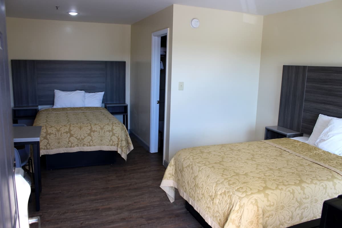 A hotel room with two beds, a desk, and a wardrobe.