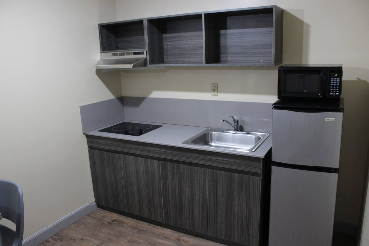 A compact kitchen with a built-in microwave, a sink, and a stove.