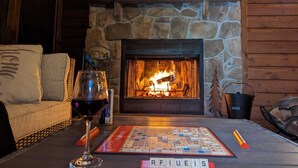 Ein gemütliches Zimmer mit Kamin aus Stein, einem Scrabble-Spiel und einem Glas Rotwein.