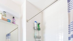 A bathroom with a white bathtub, a sink with a mirror above it, and a shower area with a glass door.