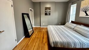 A bedroom with a bed, a mirror, and artwork on the walls.