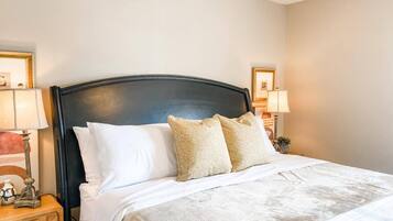 A neatly made bed with white and patterned pillows, a dark headboard, and bedside lamps.