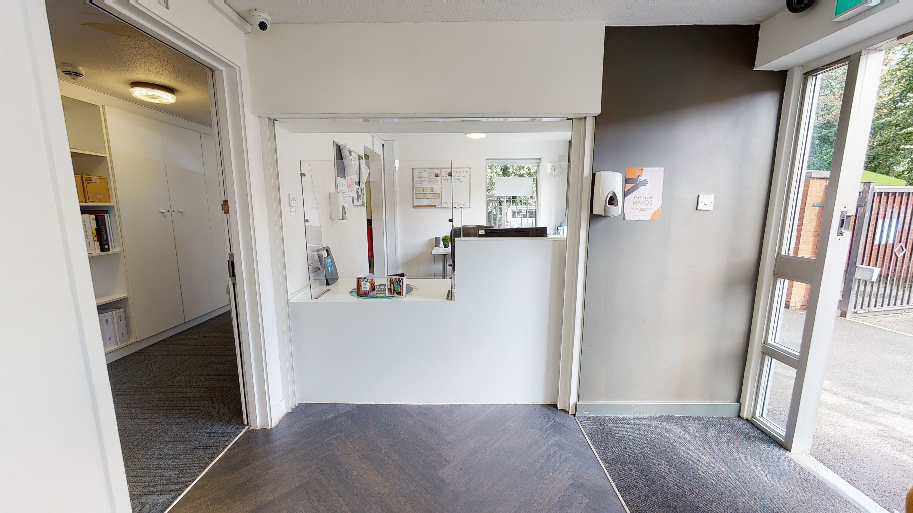A reception area with a desk, a phone, and a sign instructing to clean hands.