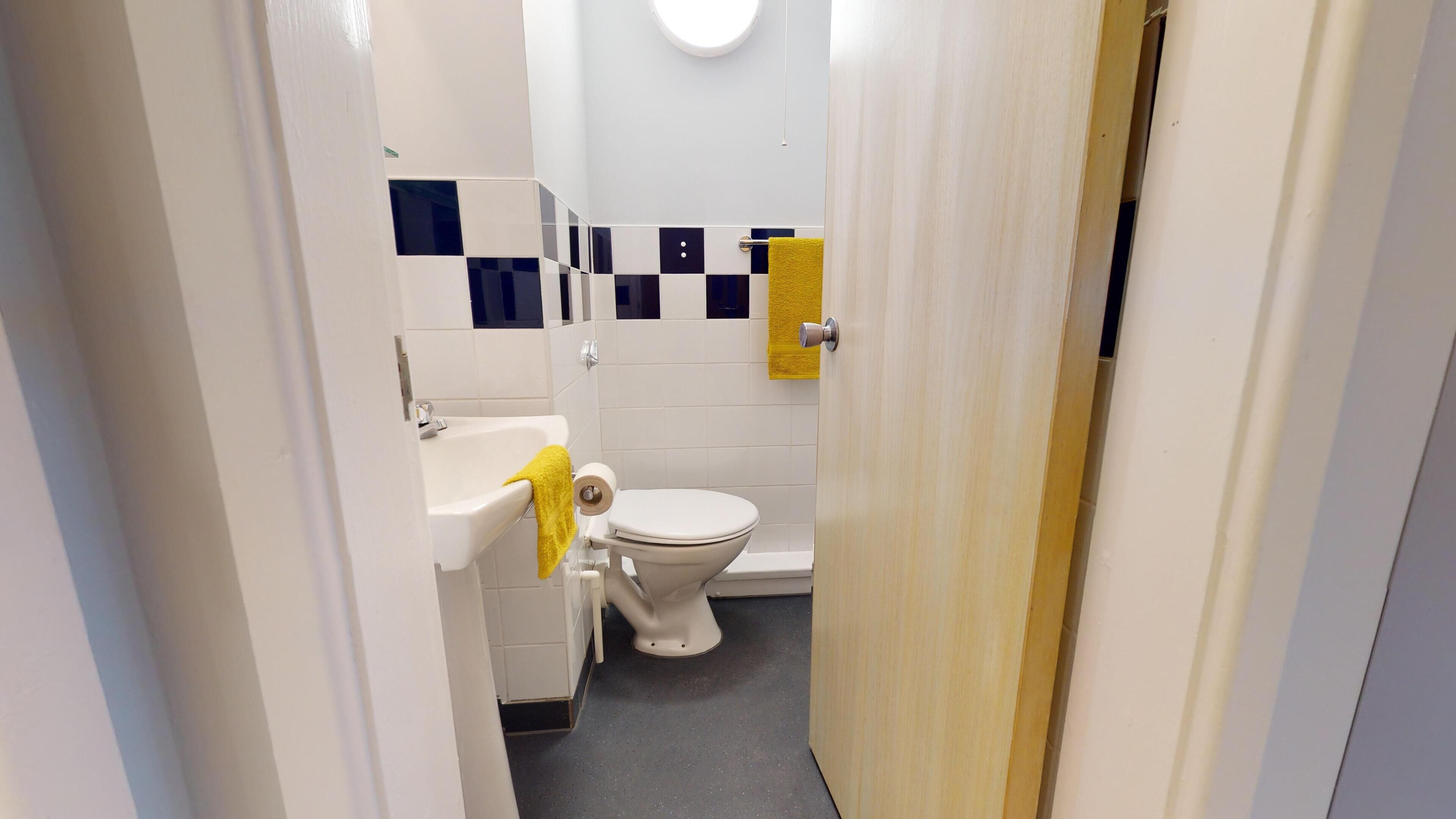 Pieni kylpyhuone, jossa on wc, pesuallas ja peili.