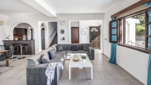 A spacious living area with a grey sectional sofa, a white coffee table, and a kitchen in the background. - Villa Argaka Vista - Three Bedroom Villa, Sleeps 6 (Argaka)