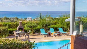 A poolside area with lounge chairs, a barbecue grill, and a view of the sea. - Villa Argaka Vista - Three Bedroom Villa, Sleeps 6 (Argaka)