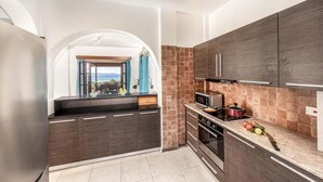 A modern kitchen with dark wood cabinets, a built-in oven, and a view through an archway to a balcony. - Villa Argaka Vista - Three Bedroom Villa, Sleeps 6 (Argaka)