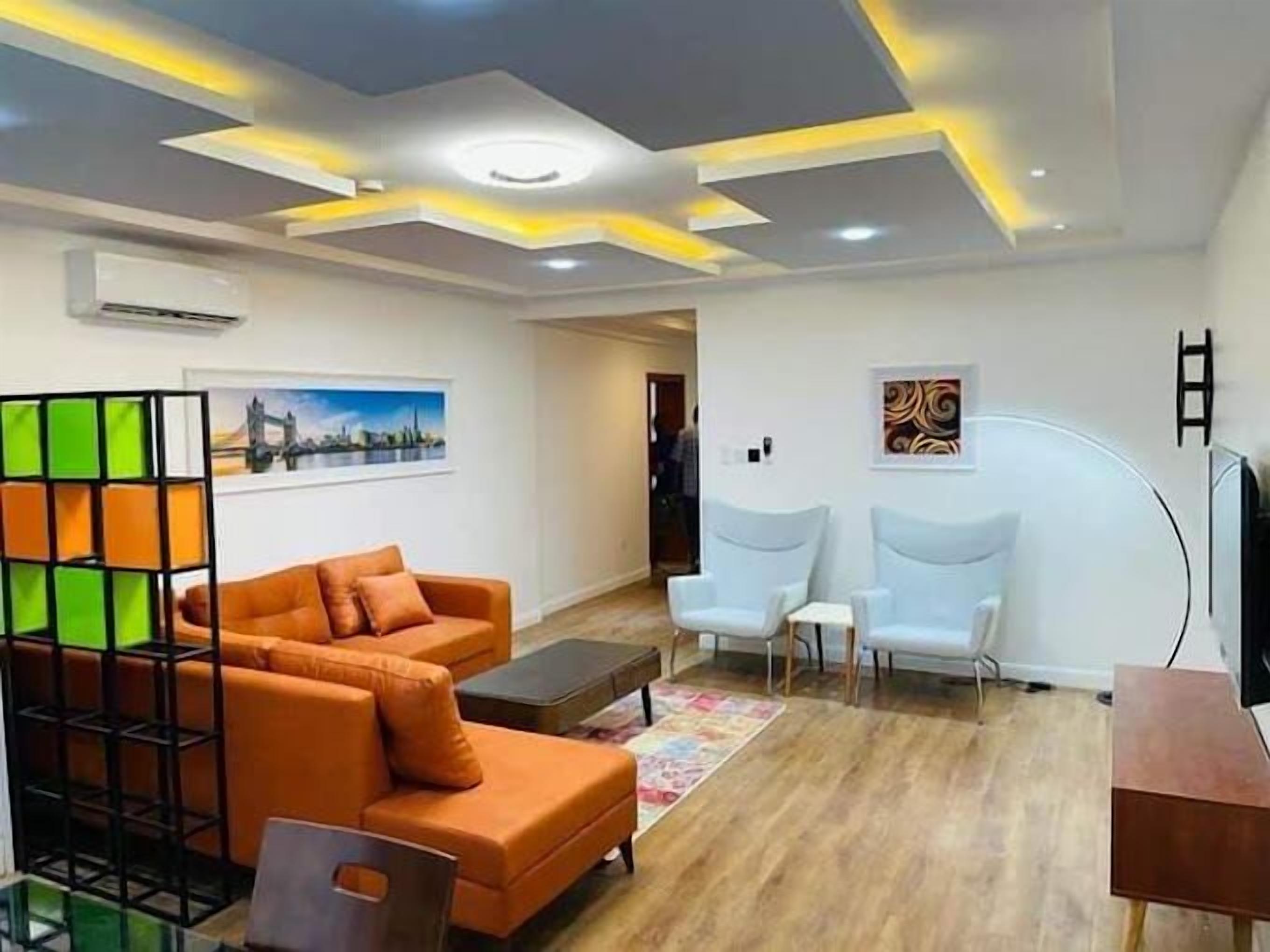A modern living room with a sectional sofa, two armchairs, a coffee table, and a TV.