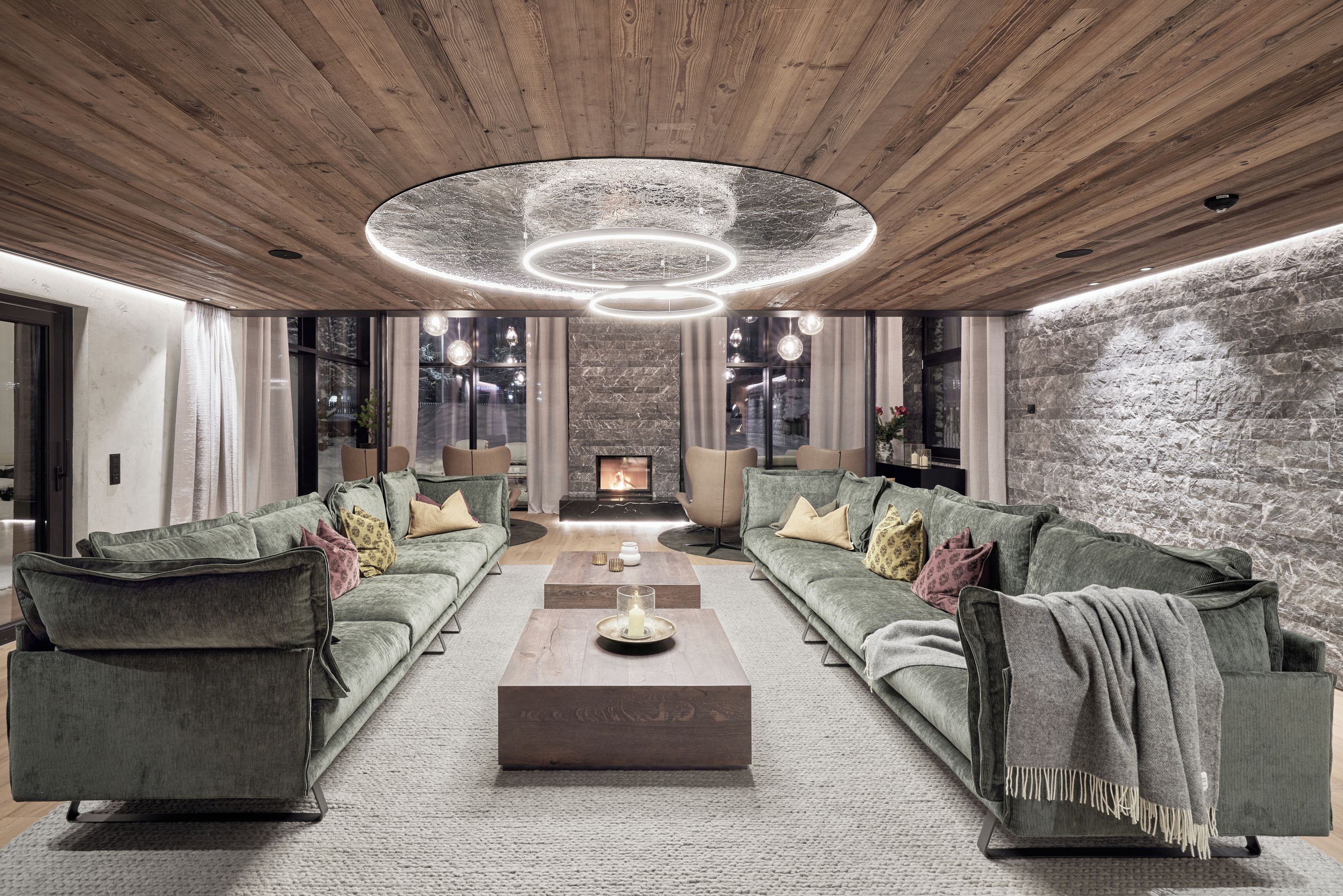 A modern living room with a fireplace, two sofas, a coffee table, and a wooden ceiling.