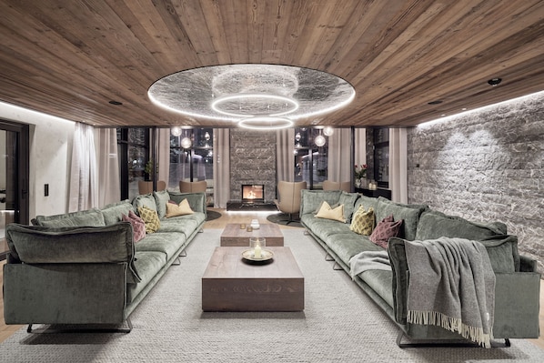 Una sala de estar moderna con chimenea, dos sofás, una mesa de centro y techo de madera.