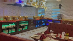 A restaurant interior with a modern design, featuring a patterned ceiling, decorative lighting, and a variety of seating options including a booth and a table with a pineapple centerpiece. - Golden Vista Hotels (Owerri)