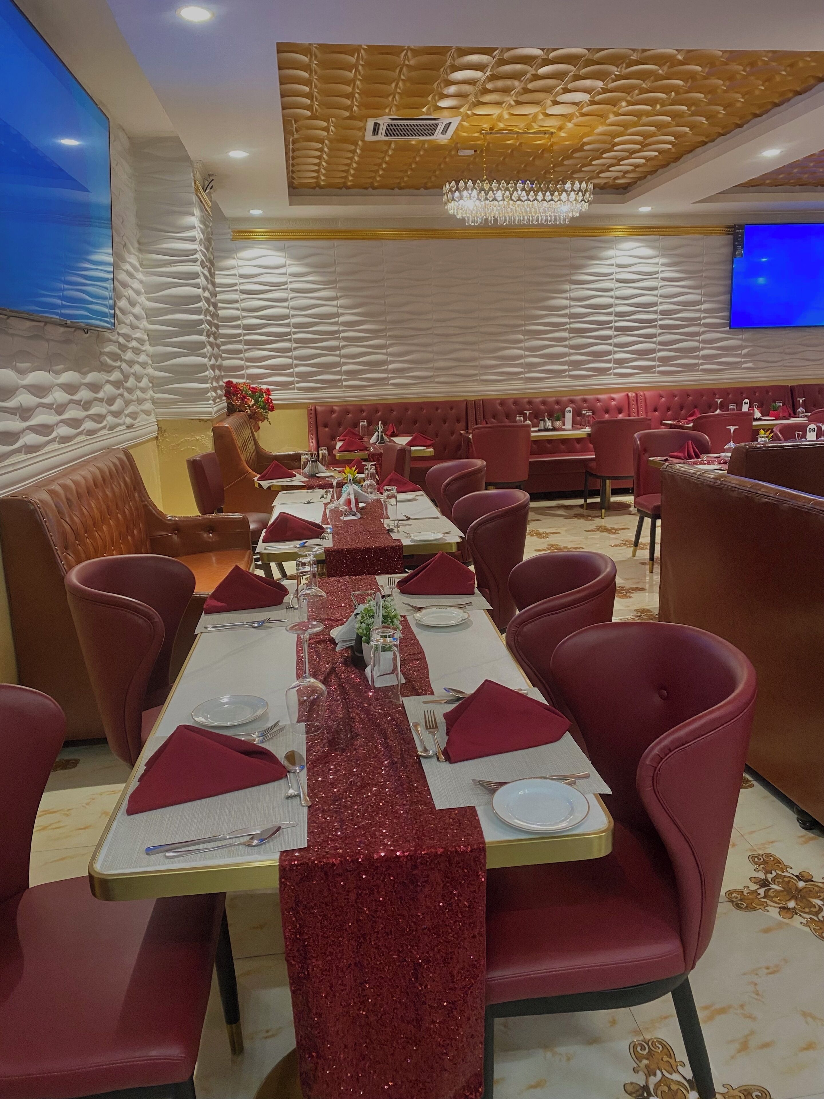 A dining area with a long table set for a meal, surrounded by red upholstered chairs.