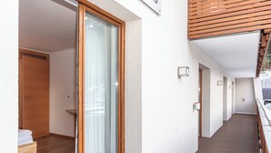 Un corridoio con pavimento in legno, una porta scorrevole in vetro e una panca in legno.