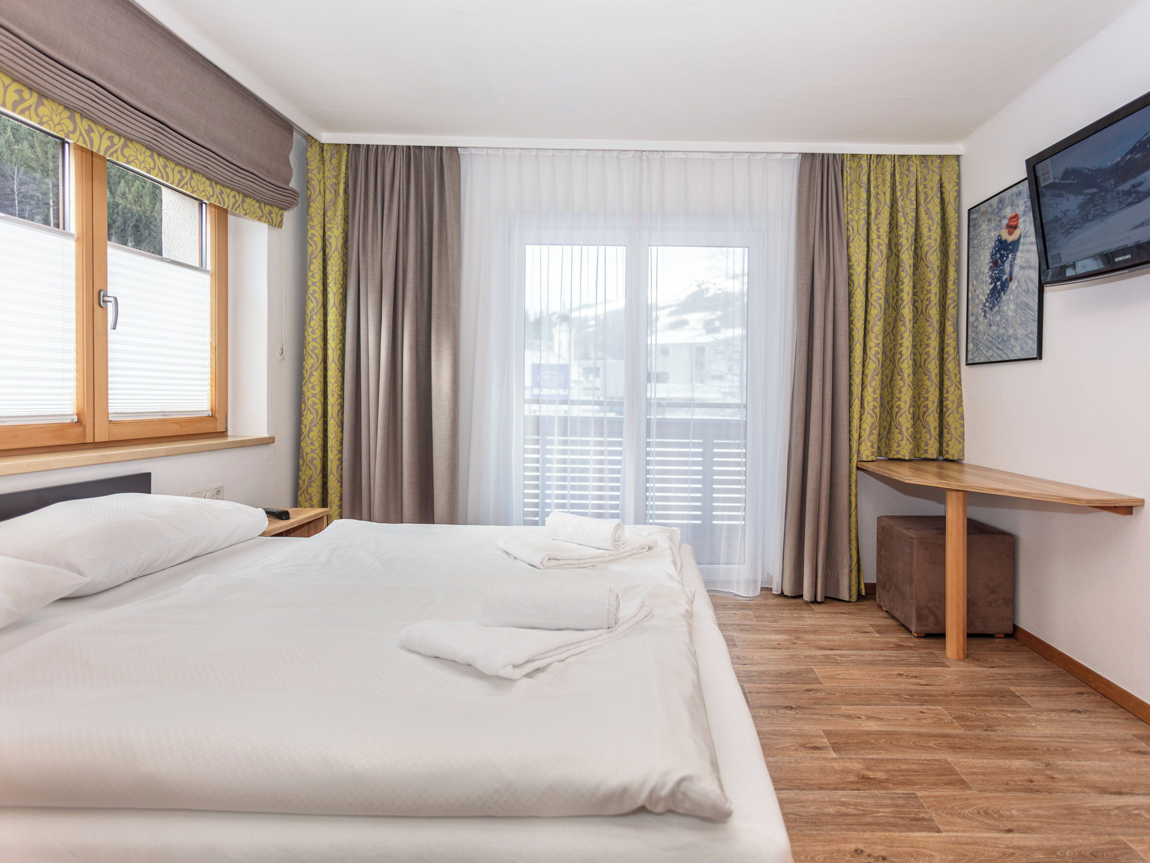 A hotel room with a bed, a desk, and a TV.