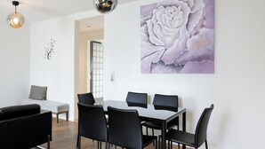 A modern dining area with a table and chairs, a sofa, and a wall-mounted flower painting. - VISIONAPARTMENTS Zurich Hardstrasse (Zürich)